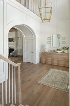 an entry way with white walls and wood floors, a chandelier hanging from the ceiling