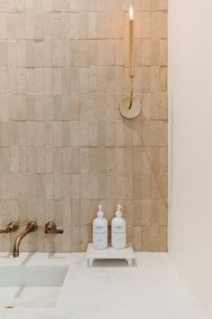 a bathroom with two soap dispensers on the counter and a candle in the wall