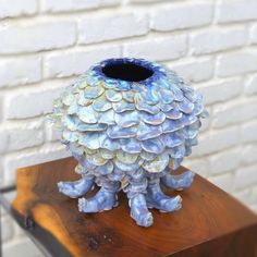 a blue vase sitting on top of a wooden table next to a white brick wall