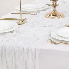 the table is set with white plates and gold place settings for an elegant dinner party