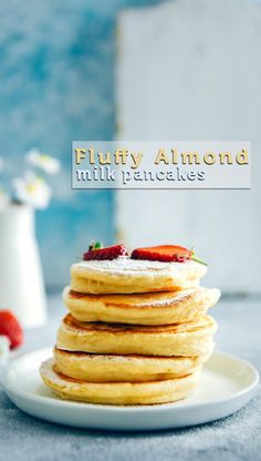 stack of pancakes with powdered sugar and strawberries