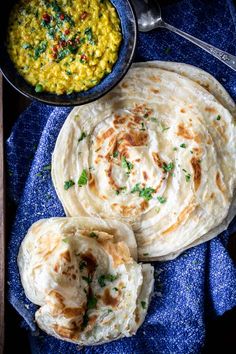 three tortillas on a blue towel next to a bowl of corn