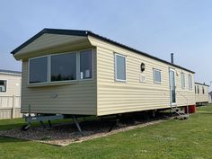 a mobile home sits in the middle of a grassy area next to two other mobile homes