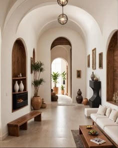 a living room filled with lots of furniture next to a wall mounted fireplace and potted plants