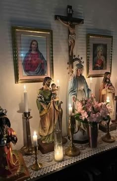 a table topped with statues and candles next to pictures