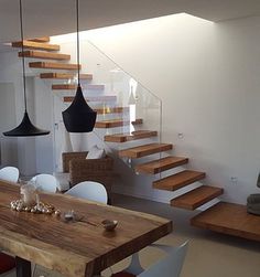 a dining room table with white chairs and wooden stairs