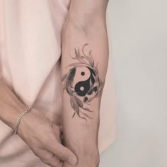 a woman's arm with a black and white yin - yang tattoo on it