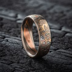 "* Price may vary depending on ring size, please inquire with us directly with your needed size for accurate pricing! This beautiful Mokume Gane ring is shown in a combination of two of our other patterns, Twist and Droplet, and our Firestorm metal combination.  The ring has a  low-dome profile and an etched and oxidized finish. The Firestorm palette features 14kt yellow gold, 14kt red gold, palladium and sterling silver. Design Details: Palette: Firestorm Pattern: Twist/Droplet Width Shown: 6mm Size Shown: 6.75 Finish: Etched & Oxidized Profile: Low Dome Price does NOT include stones or setting fees. We care about customer service and would like to hear from you! Please contact us to help create your treasured item, we take your concerns and requests to heart and will work together to cre Carved Adjustable Jewelry For Wedding, Artisan Etched Jewelry For Wedding, Unique Copper Wedding Jewelry, Round Copper Jewelry For Anniversary, Round Patina Rings For Anniversary, Unique Etched Jewelry For Wedding, Unique Etched Wedding Jewelry, Artisan Engraved Ring For Wedding, Unique Bronze Wedding Rings