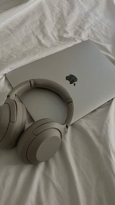 an apple laptop and headphones on a bed