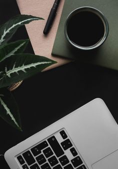 a laptop computer sitting on top of a desk next to a cup of coffee