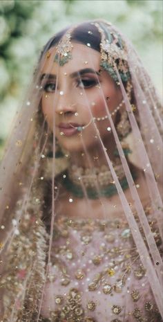 a woman wearing a veil with gold sequins and beads on her head is looking at the camera