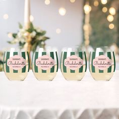 four wine glasses with labels on them sitting on a table in front of some lights