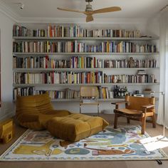 a living room filled with lots of books and furniture next to a large book shelf