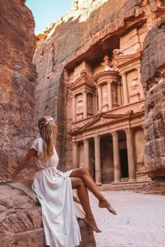 a woman is sitting on a rock in front of the ancient city of tourist attraction