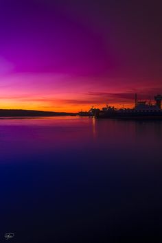 the sky is purple and orange as the sun sets in the distance over the water