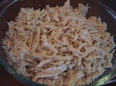 shredded chicken in a glass bowl sitting on a wooden table top, ready to be cooked