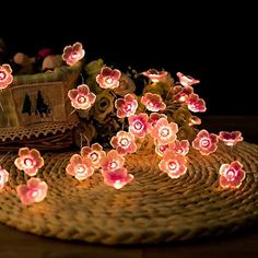 pink flowers are lit up on a wicker basket with other items in the background