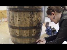 a woman working on a large wooden barrel