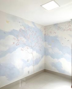 an empty room with a tree painted on the wall and clouds painted on the walls