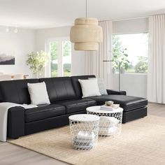 a modern living room with black leather sofa and white coffee table in front of large windows