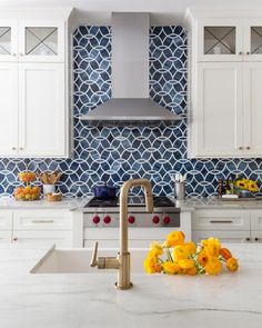 a kitchen with white cabinets and yellow flowers on the counter top in front of an oven