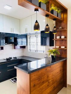 a kitchen with black and white cabinets, an island counter top and hanging lights above it