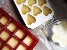 two trays filled with heart shaped ice cubes next to an uncooked cake