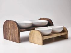 four bowls on a wooden stand with white plates in front of the bowl holder and one sitting on it's side