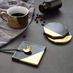 two black and gold coasters next to a cup of coffee on a gray surface