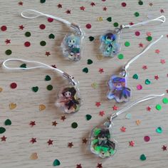 three charms with images of characters on them sitting next to confetti sprinkles