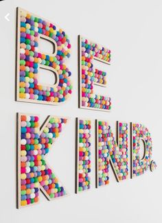 the words be kind spelled with colorful candies on a white wall in an art gallery