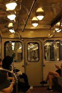 people are sitting on the subway train and looking at their cell phones while they read