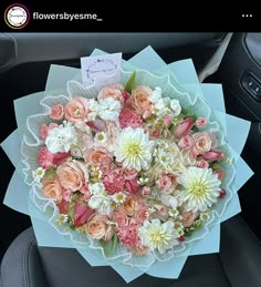 a bouquet of flowers sitting in the back seat of a car with a note on it