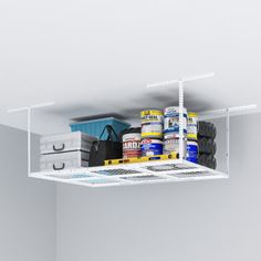 an overhead shelf with paint and other items in the corner, including two bins