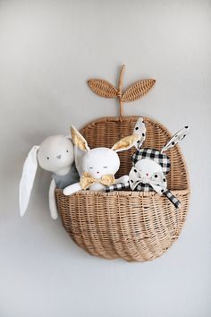 two stuffed animals in a wicker basket hanging on the wall next to each other