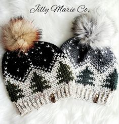 two knitted hats with pom - poms are laying on top of white fur