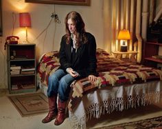 a woman sitting on top of a bed next to a lamp