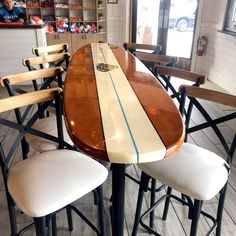 the surfboard is sitting on top of the bar stools at the dining table