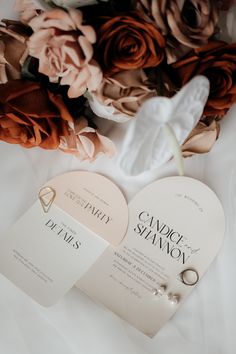 two wedding rings are laying on top of the cards and flowers in front of them