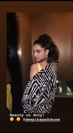 a woman standing in an elevator with her back turned to the camera and wearing a zebra print top