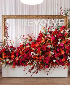 red and white flowers are arranged in front of a gold framed sign that says remove