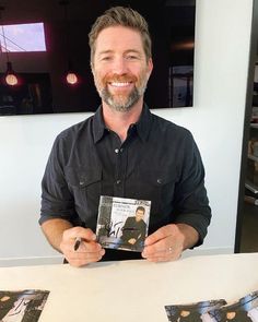 a man sitting at a table holding up a cd with an image of himself on it