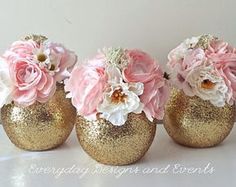 three gold vases with pink and white flowers in them