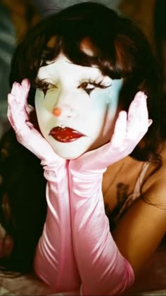 a woman with her hands on her face posing for the camera while wearing pink gloves