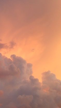 the airplane is flying high in the sky at sunset or dawn, with clouds behind it