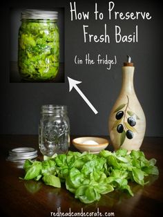 a jar filled with fresh basil sitting on top of a table next to some jars