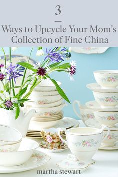 there are many dishes and cups on the table with flowers in them, including one teapot