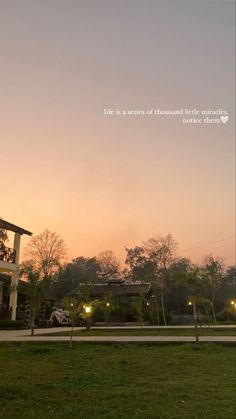 the sky is pink and purple as the sun sets over a house with trees in the foreground