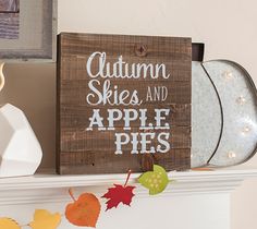 a wooden sign that says autumn skies and apple pies hanging on a mantel