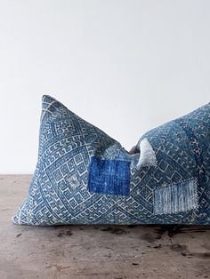 a blue pillow sitting on top of a wooden table next to a white wall and floor